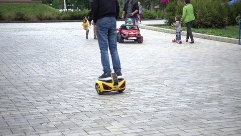 Children ride balancing Giroboard motorized scooter - outdoor city street Stock Footage