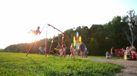Children ride on the swings at the playground in a beautiful sunny day Stock Footage