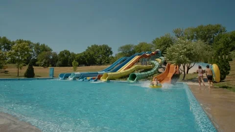 Children riding down an orange slide in a water park. Video stock 299917066