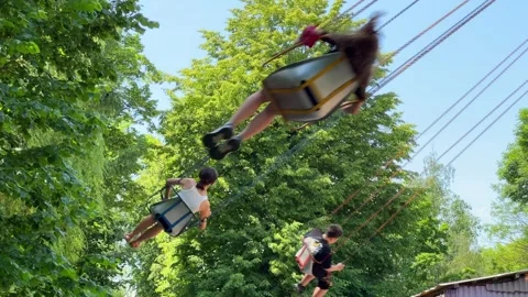 Children riding a swing carousel ride at an amusement park Stock-Footage 341662936
