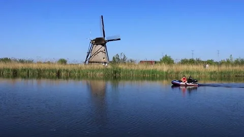 Children rowing in the river near the windmill Stock Footage 147868887