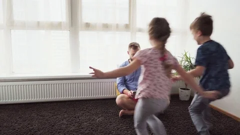 Children run to father sit down on floor and look at tablet screen Stock Footage 82422452