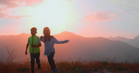 Children run through a field in the mountains at dawn Stock Footage 236747845