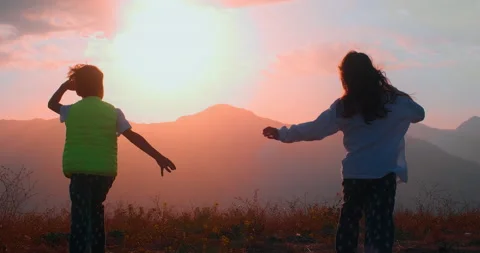 Children run through a field in the mountains towards the dawn Stock Footage 236754635