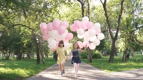 Children run through the Park with a huge bunch of colorful balloons. two little Stock Footage