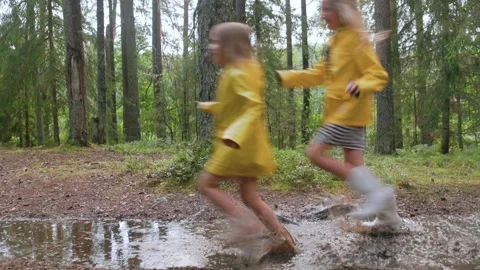 Children running and splashing through puddle on forest path after rain in .. Stock Footage 314674012