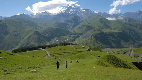 Children running down the hill on background of scenic view of Kazbeg mountain Stock Footage 255309443