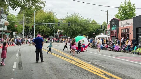 Children running with giant inflatable beach ball in street parade Stock Footage 339116535