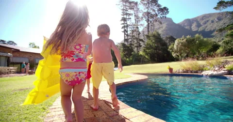Children running with lilo towards swimming pool Stock Footage