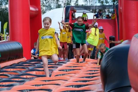 Children Running Through Inflatable Obstacle Course Together Stock Photos