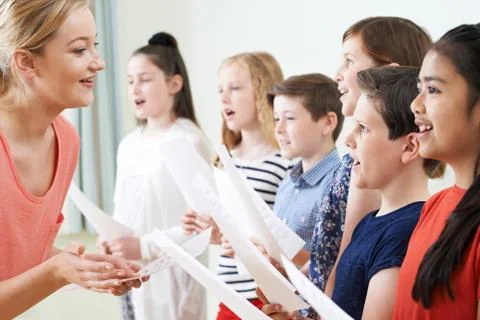 Children In School Choir Being Encouraged By Teacher Stock Photos
