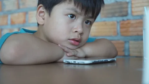 Children sit with hands on the table looking front on wall background, 스톡 동영상 88623874