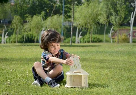 Children sit on the lawn and the house that makes Stock Photos