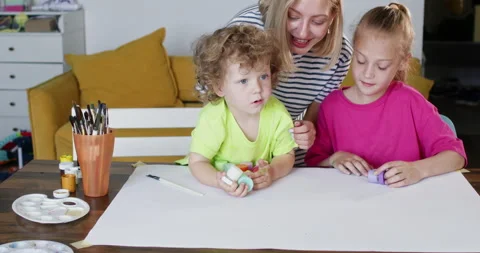 Children sit at table and examine different colors of paint Vidéo 285323224