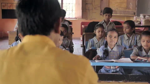 Children sitting on the benches studying while teacher is teaching in classroom Stock Footage 133970023