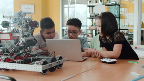 Children sitting at the table around the laptop in a class at a robotics lesson Stock Footage 242495992