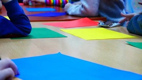 Children sitting at the table with colored sheets of paper at a creative lesson Stock Footage 171029731