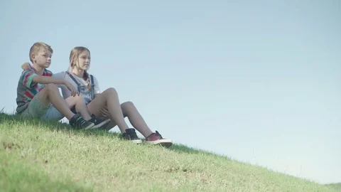 Children sitting together on hillside looking at view Stock Footage 75179749