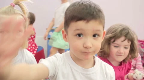Children sitting waving  hands to camera. 스톡 동영상 62196958