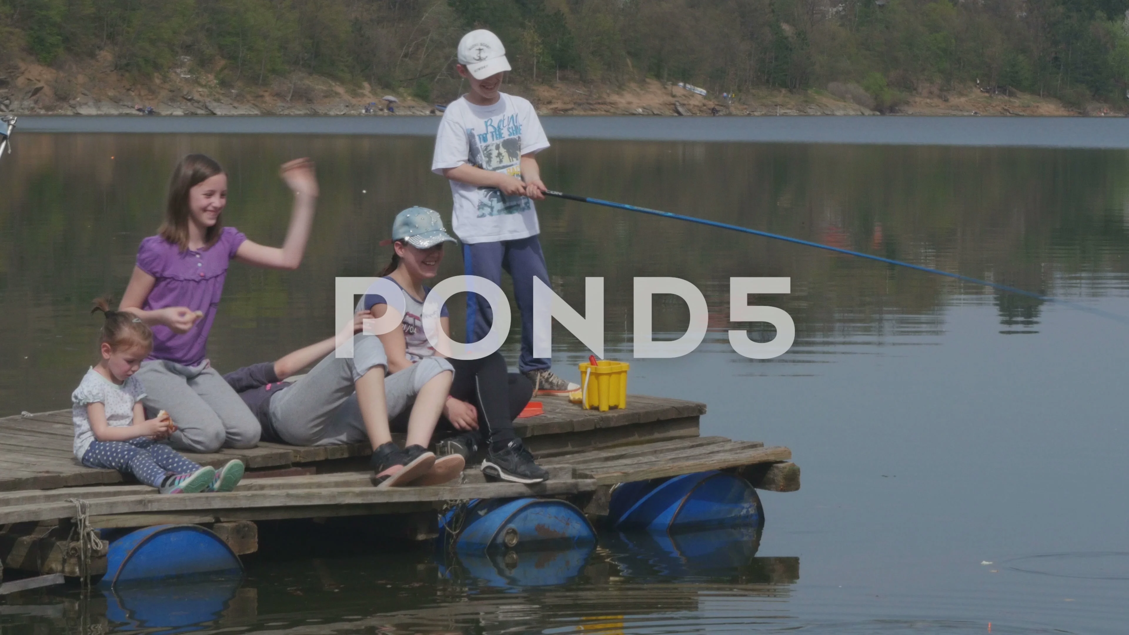 Children sitting on wooden dock at lake,, Stock Video