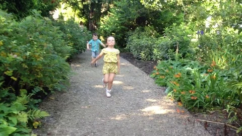 Children Skipping Down A Garden Path in Summertime Stock-Footage 72380707