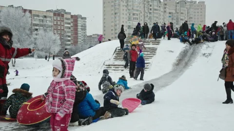Children slide down a snow hill in the park at the weekend Vídeo Stock 59139954