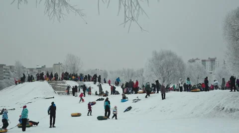Children slide down a snow hill in the park at the weekend Stock Footage 59141291
