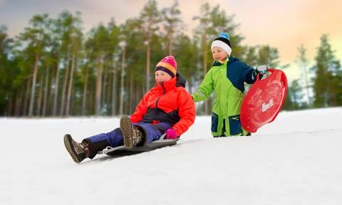 Children sliding on sleds down snow hill in winter Stock Photos