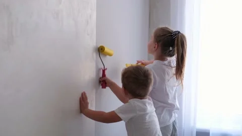 Children smooth the wallpaper on the wall with a roller. Stock Footage 150591859