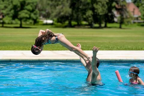 Children splash joyfully in a sunlit pool Stock Photos