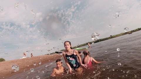 Children splash water and throw sand into the camera. Summer sunny day. Weekend Stock Footage 164090153