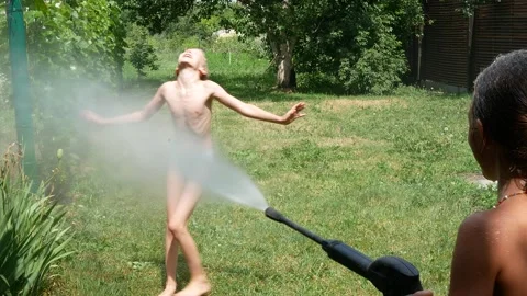 Children sprinkle water on each other from a high-pressure washer Vídeos de archivo 245914402