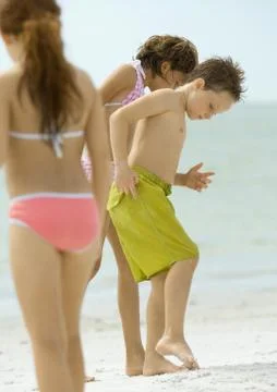 Children standing on beach, looking down at sand Stock Photos