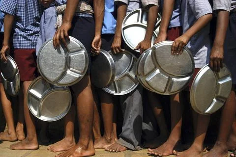 Children standing in queue with round molded stainless steel plate for lun... Stock Photos