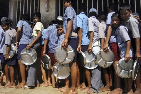Children standing in queue with round molded stainless steel plates for lu... Foto stock