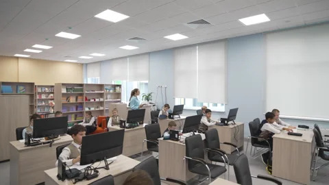 Children study in modern computer lab as teacher observes Stock Footage 308957725