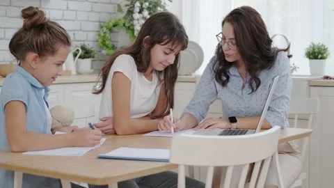 Children study remotely online on a laptop. Mom helps children with homework Stock Footage 142937367