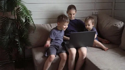 Children studying technology alongside their experienced older brother indoors. Stock Footage 331127368