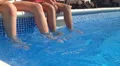 Children swinging feet in swimming pool (with a shove at final) HD Footage