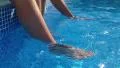Children swinging feet in swimming pool - close up HD Footage