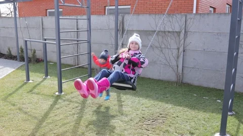 Children swinging on a swing in a backyard Stock Footage 150480572