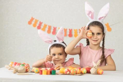 Children at the table decorated for Happy Easter. Girl and boy have fun getting Stock Photos