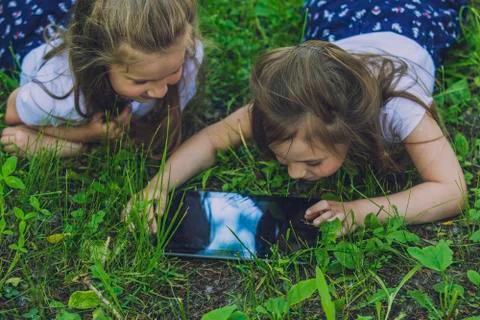 Children with the tablet lying in the grass 写真素材