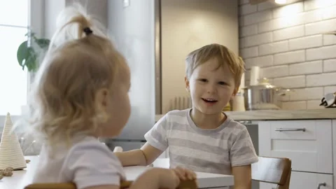 Children talk while sitting at the Christmas table. Boy and girl decorate and Stock Footage 164577370