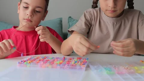 Children threading colorful beads at table Stock Footage 315395580