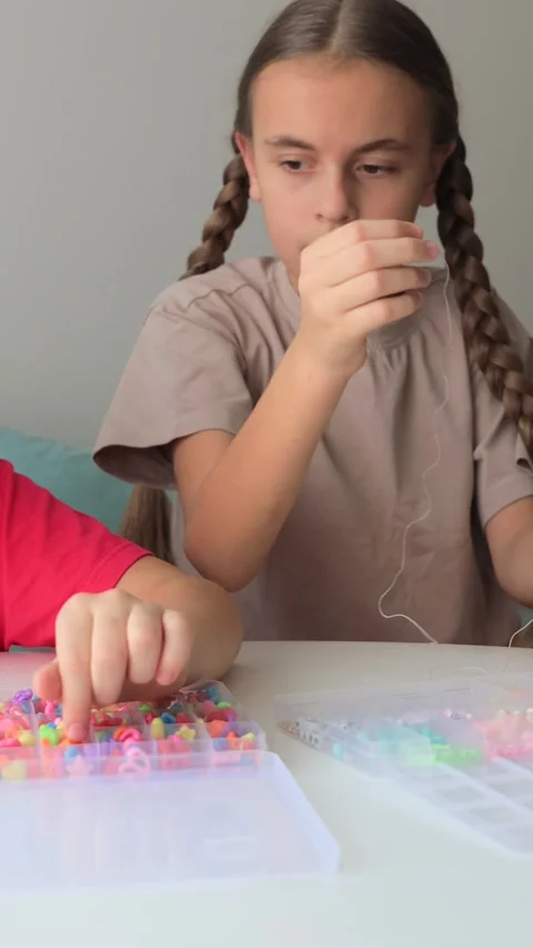 Children threading colorful beads at table Stock Footage 315395603