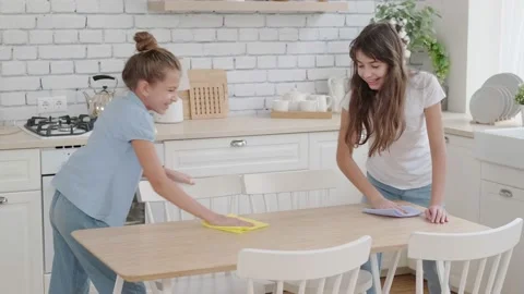 Children tidy up the kitchen, wipe the table. Little sister helps older sister Vidéo 142936939