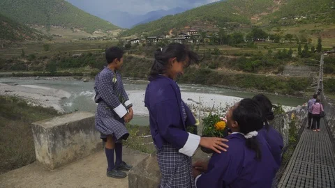 Children in traditional dress laughing at the edge of bridge in Punakha, Bhutan Stock Footage