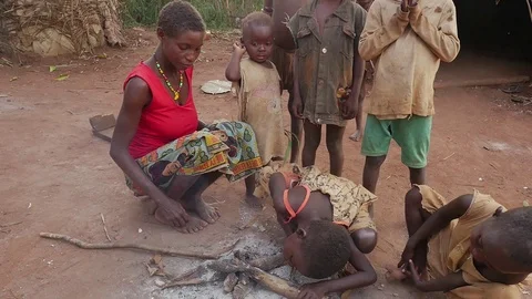 Children try to stoke the fire under the gaze of the mother Stock Footage 107309628