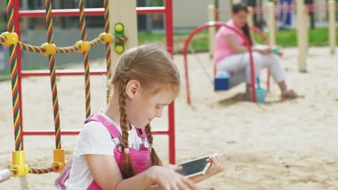 Children use a computer tablet, walk on the playground Video stock 107957026